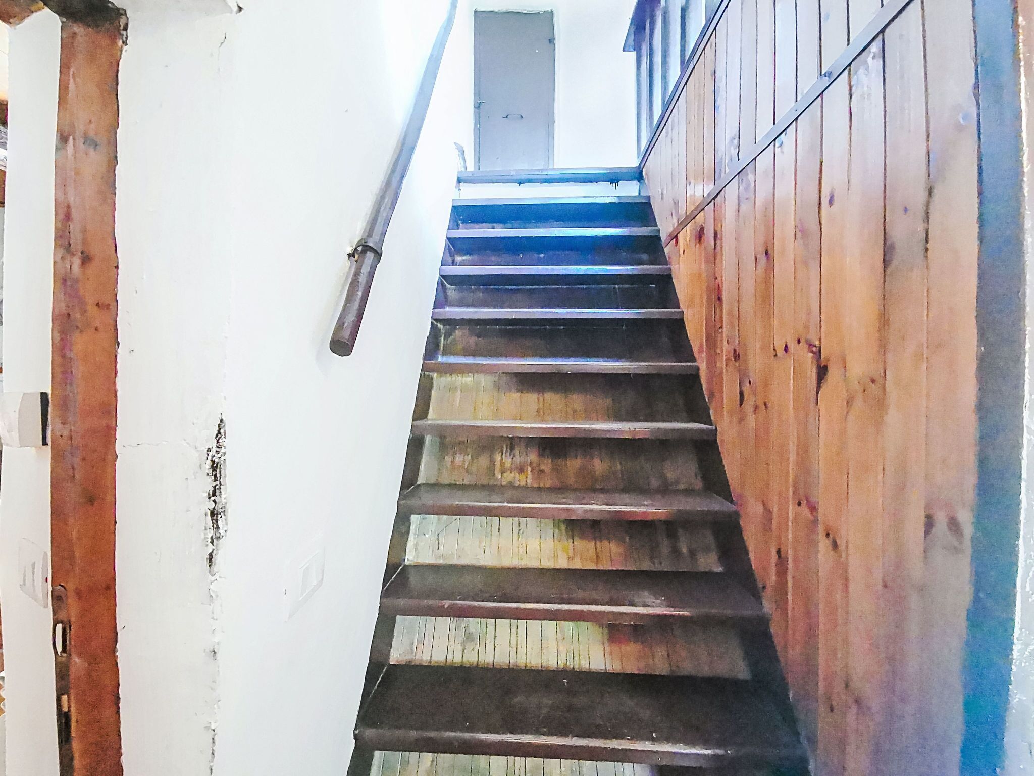 Una scala in legno con corrimano che conduce a una porta in cima.