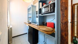 Eine kleine Küche mit Mikrowelle, Kaffeemaschine und einer Holzausziehtafel.