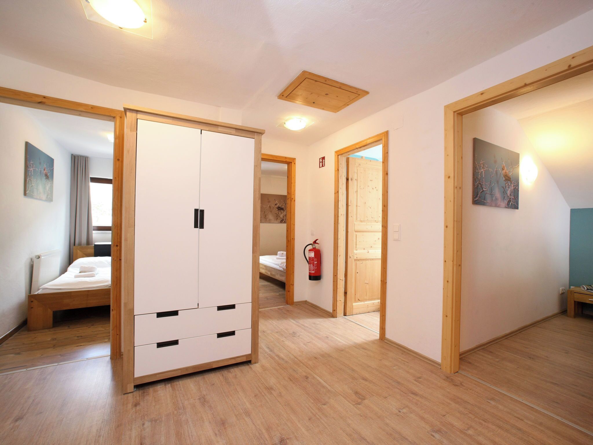 Ein Hotelzimmer mit Holzboden, einem Bett, einem Kleiderschrank und einem Gemälde an der Wand.