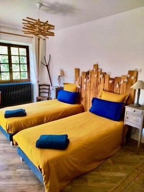 A room with two beds, a wooden headboard, a nightstand, and a window.