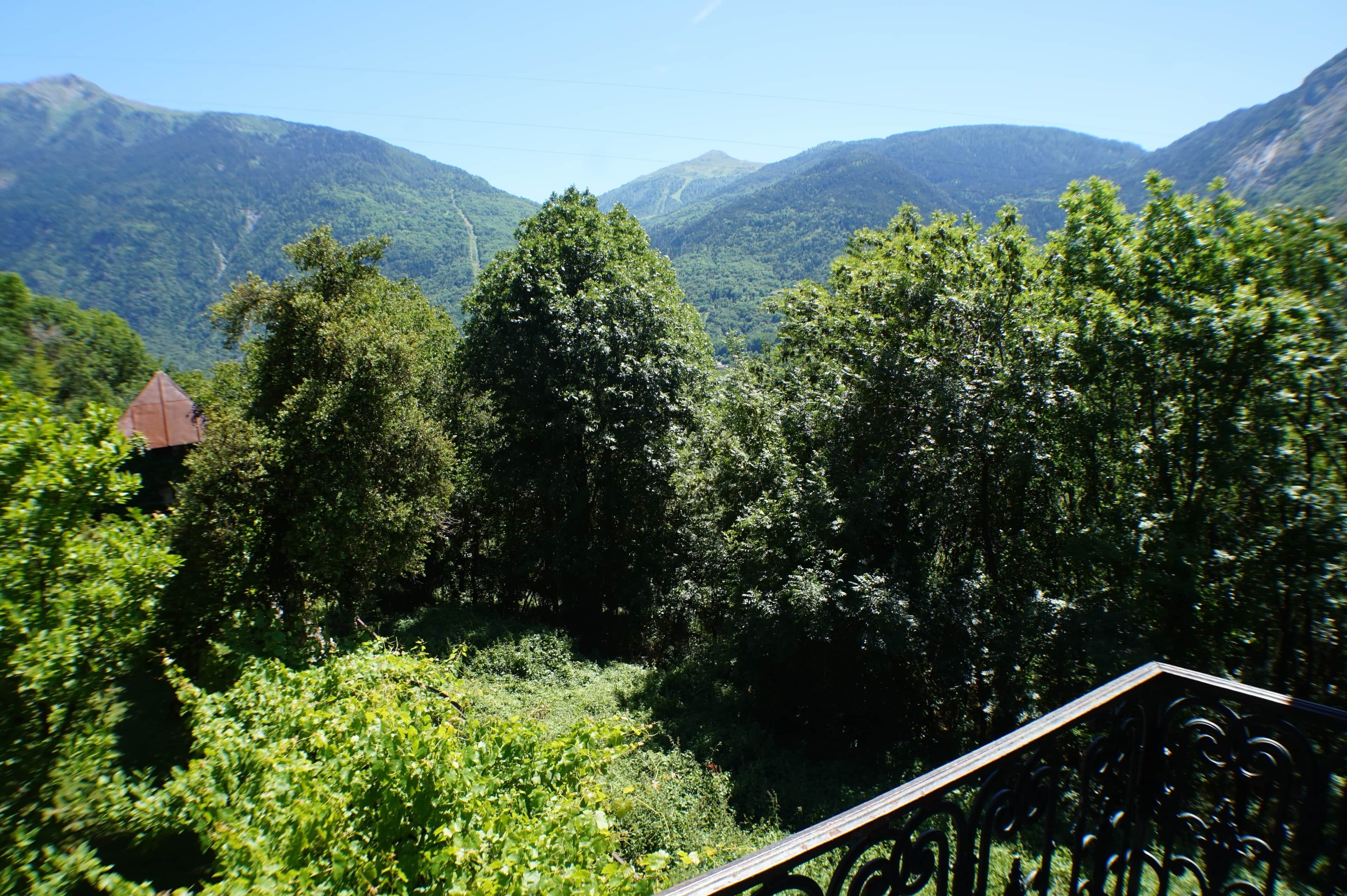 Un paysage montagneux, caractérisé par une végétation luxuriante et un petit bâtiment surmonté d’un toit rouge.