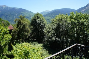 A mountainous landscape with dense greenery and a small building with a red roof.