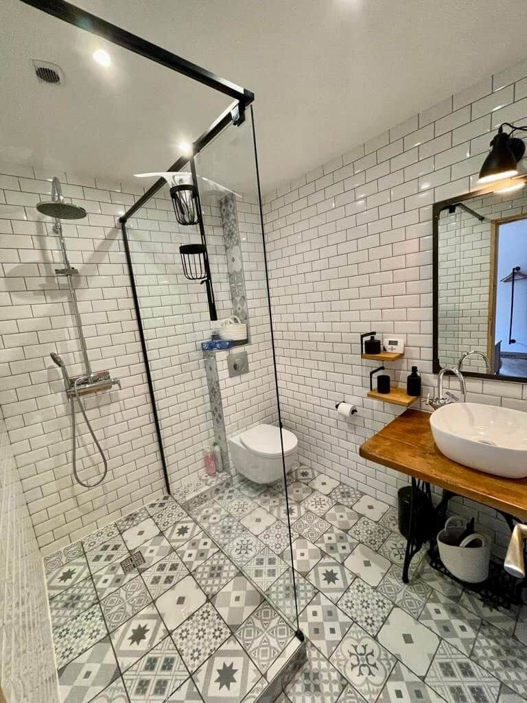 A modern bathroom with a glass shower enclosure, a white toilet, and a wooden vanity with a large sink.