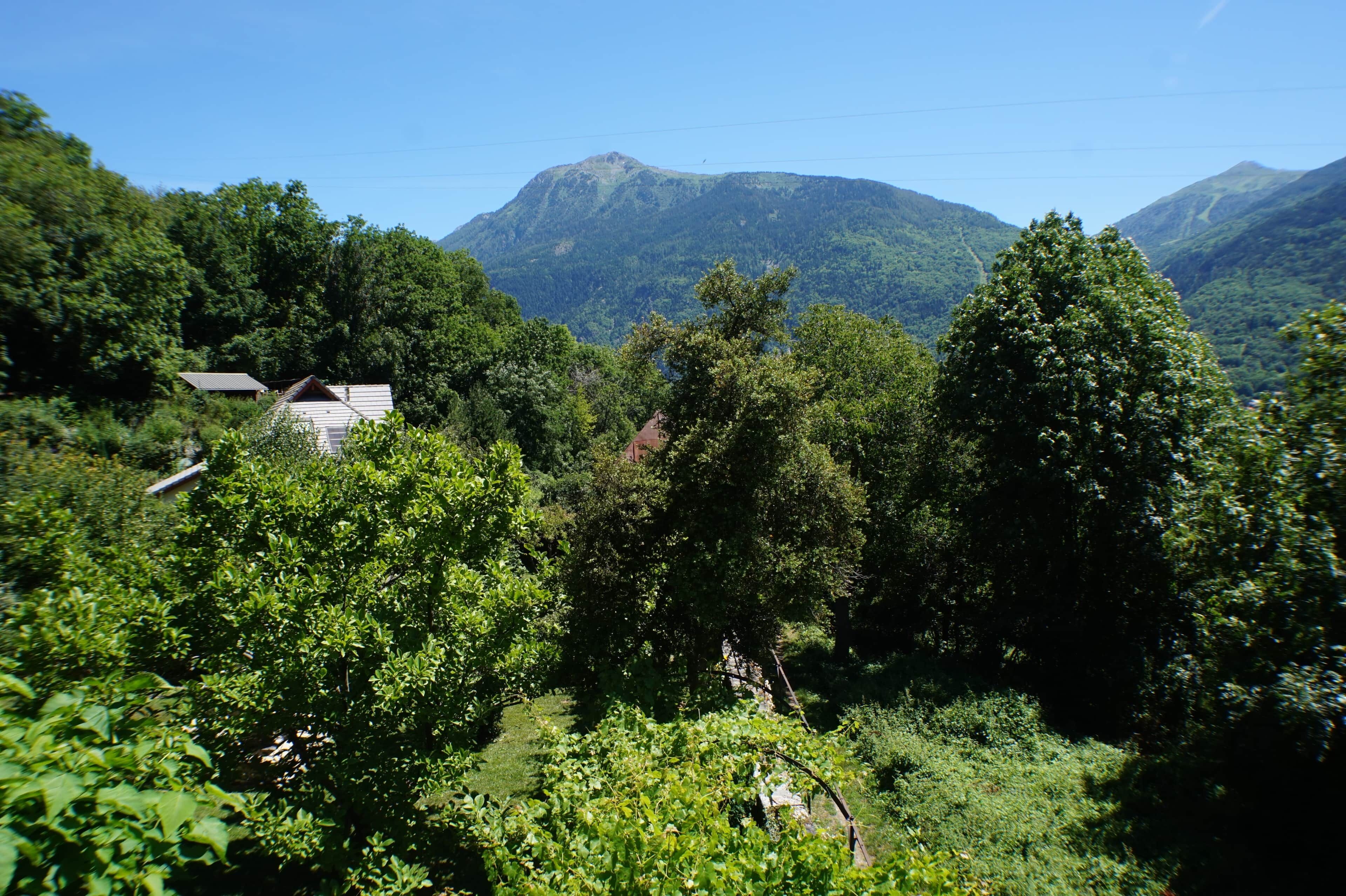 Un paysage montagneux, caractérisé par une végétation luxuriante et un petit bâtiment doté d’un toit en pente.