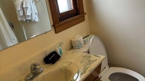 A bathroom with a marble sink, a toilet, a window, and a towel rack.
