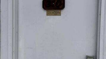 A white door with a non-smoking sign and a metal plate with numbers.
