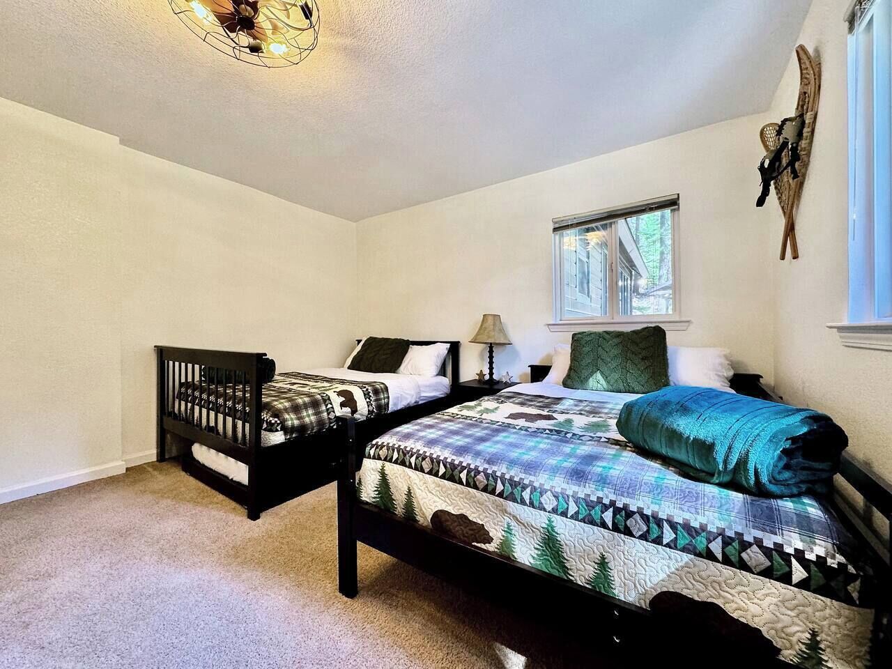 A bedroom with two beds, a window, and a wall-mounted decoration.