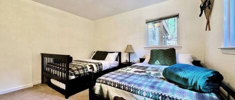 A bedroom with two beds, a window, and a wall-mounted decoration.
