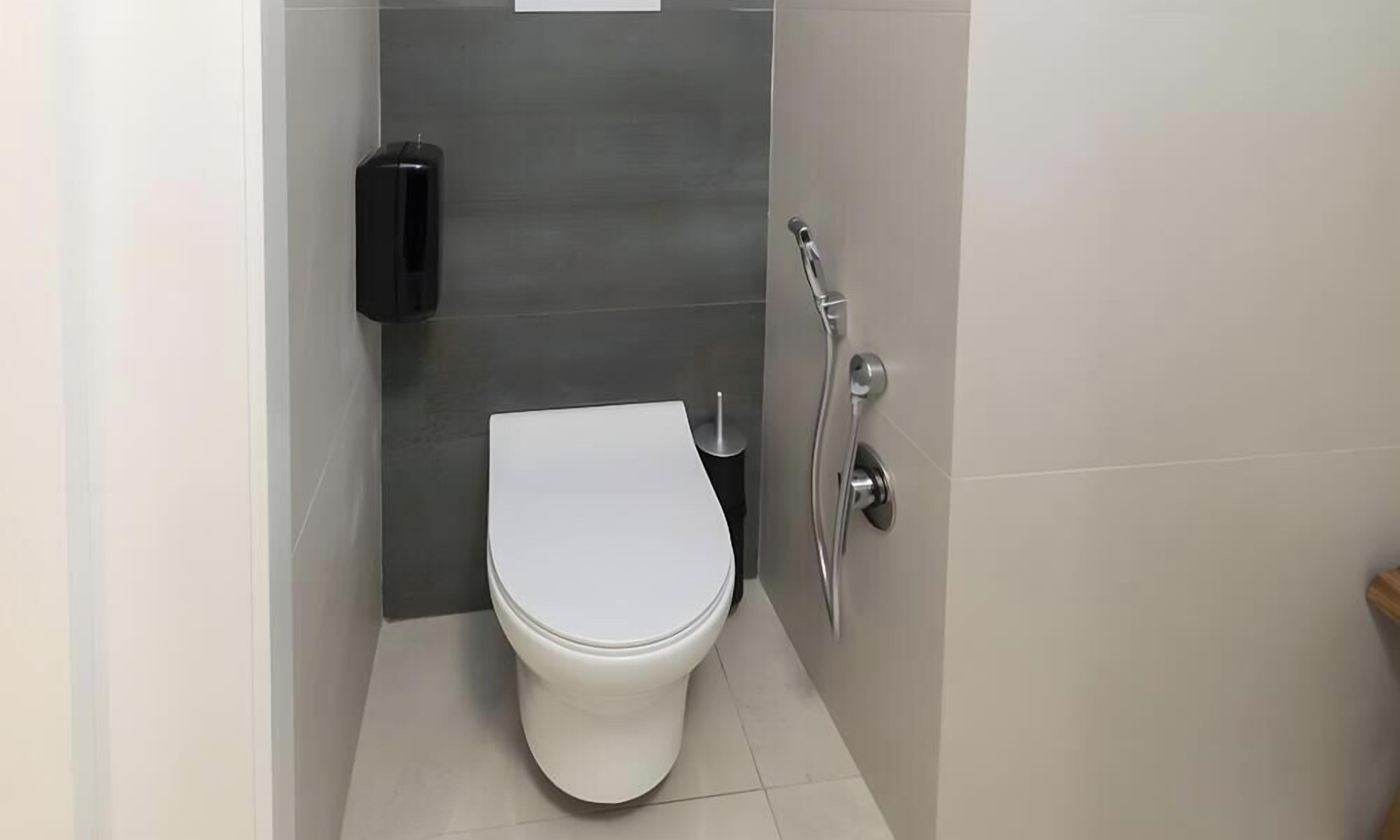 Ein modernes Badezimmer mit Toilette, Handtrockner und Duschkopf.
