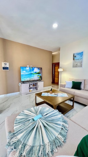 Un salon comprenant un téléviseur, un canapé, une table basse et un tapis décoratif.