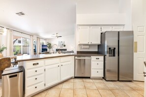 Een moderne keuken met witte kastjes, roestvrijstalen apparatuur en een vaatwasser.