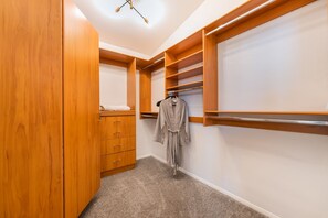 A walk-in closet with wooden cabinetry, a robe hanging, and a shelf unit. - Family Resort Home: Pool, Game Room & Mountain Views — Sleeps 12, EV Charging (Las Vegas)