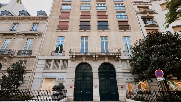 A multi-story building with a classical architectural style, featuring a prominent entrance with double doors, a balcony on the second floor, and a 'Dior' store on the ground floor. - Champs-elysees Apartment for 6 Guests (Paris)
