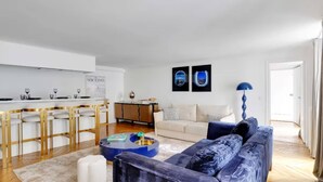 A modern living room with a sofa, a coffee table, and a dining area with chairs and a table. - Champs-elysees Apartment for 6 Guests (Paris)