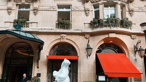 A building facade with arched windows, a white bear sculpture, and a sign reading 'PLAZA ATHLETEN'. - Champs-elysees Apartment for 6 Guests (Paris)