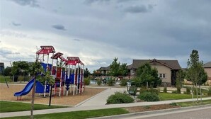 A playground with climbing structures and a slide, surrounded by a residential area with houses and greenery. - Modern luxury home - great for families (Golden)