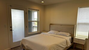 A bedroom with a bed, a nightstand, a door, and a window. - Modern luxury home - great for families (Golden)