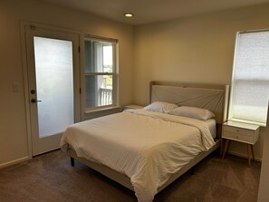 Ein Schlafzimmer mit einem Bett, einem Nachttisch, einer Tür und einem Fenster.