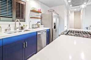 A modern kitchen with a stainless steel refrigerator, a dishwasher, and a large island with a sink. - Uncork & Unwind in Paso Robles Wine Country (Paso Robles)