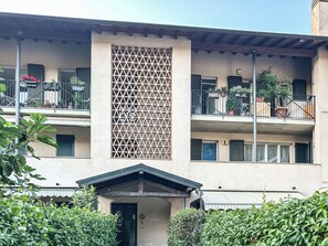 Ein mehrstöckiges Gebäude mit Balkonen, einem Gitterfenster und einem kleinen Eingang.