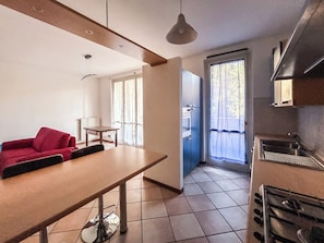 Eine kompakte Küche mit Herd, Spüle und einer Essecke mit Tisch und rotem Sofa.