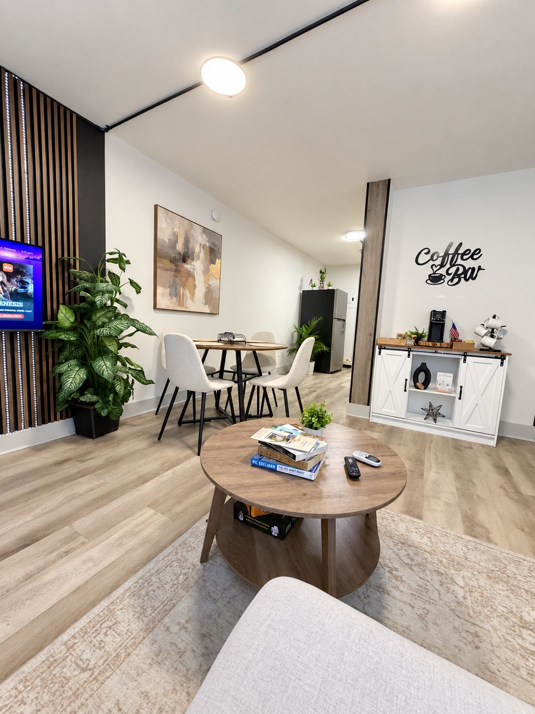 A modern living room with a round coffee table, a television, and a coffee bar.
