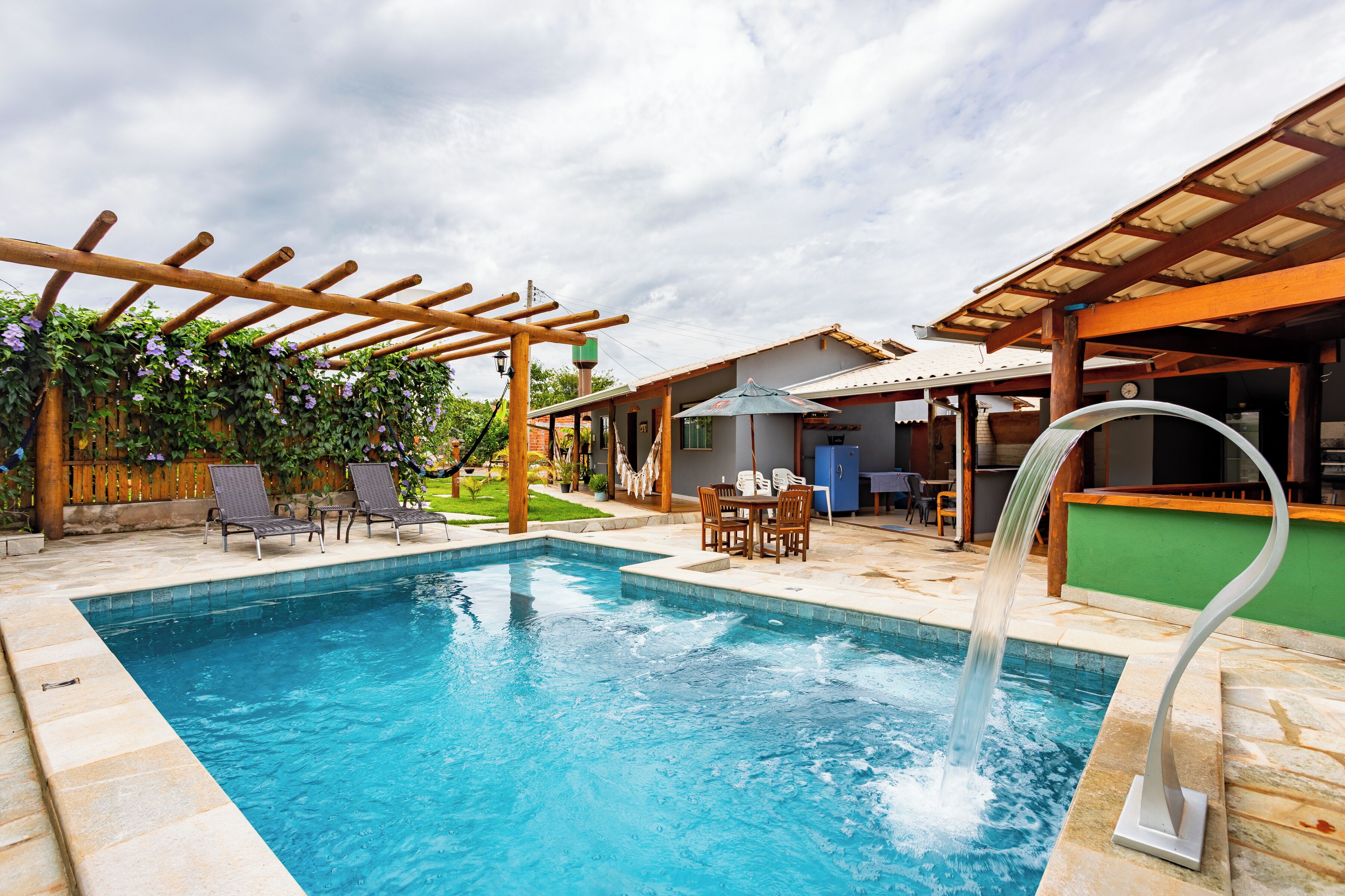 Piscina con pérgola, mobiliario exterior y zona cubierta.