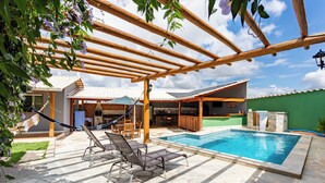 Ein Pool mit Liegestühlen, einer Pergola und einer Steinterrasse.