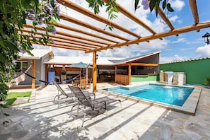 Una piscina con sillas de descanso, una pérgola y un patio de piedra.