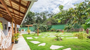Ein Innenhof mit einer Holzpergola, einem Steinweg und üppigem Grün.