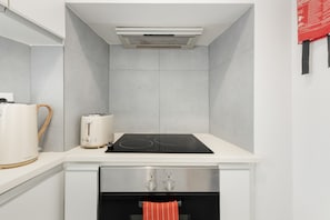 A kitchen with a white countertop, a toaster, a kettle, a stove, and a built-in oven. - Madragoa Boutique Studio (Lisbon)