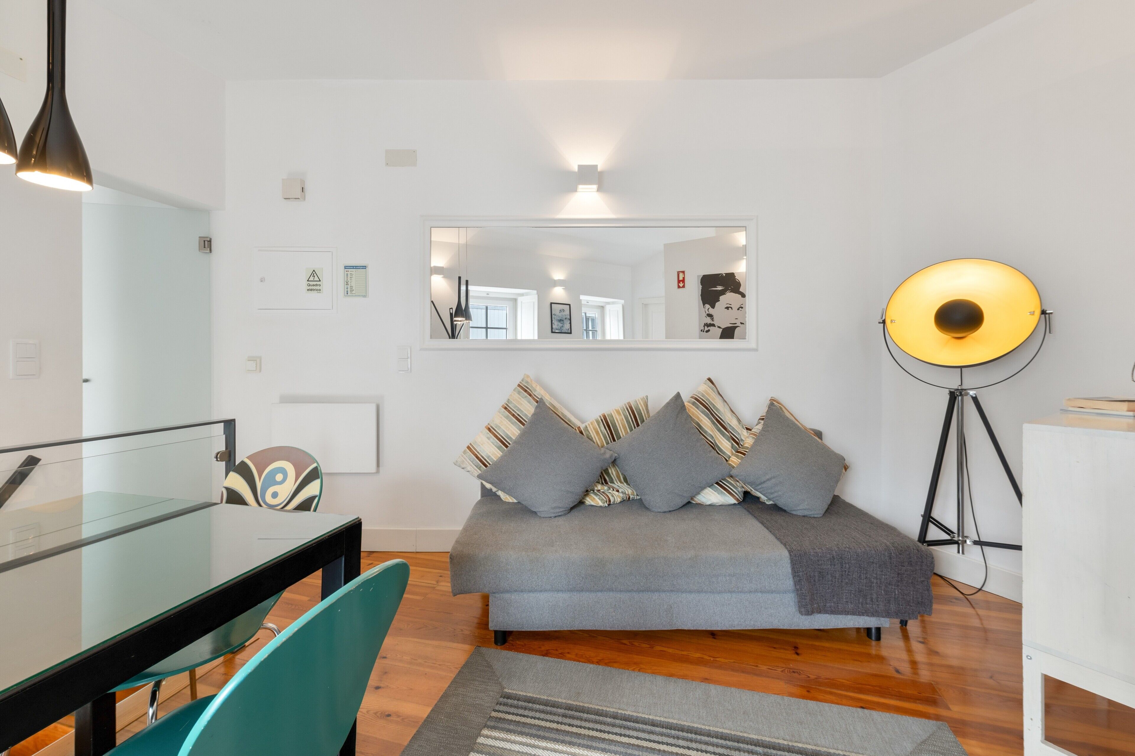 Un moderno salón con un sofá, una mesa de comedor de vidrio y una lámpara de pie.