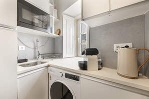 A modern kitchen with a built-in dishwasher, a microwave, a coffee maker, and a kettle. - Madragoa Boutique Studio (Lisbon)