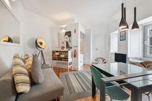 Un salon moderne avec un canapé, une table à manger et des luminaires suspendus.