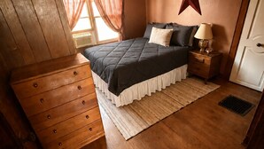 A bedroom with a bed, a dresser, a nightstand, a star decoration, and a window with curtains.