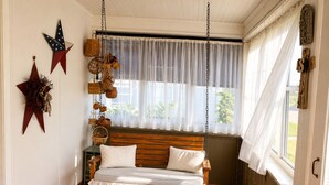 A room with a wooden bench, white cushions, a hanging basket, and a star decoration on the wall.