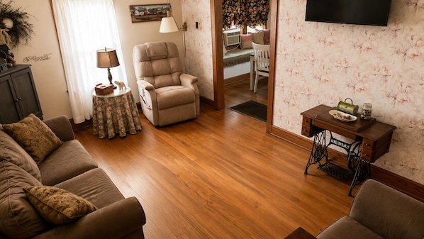 Una sala de estar con sofá, sillón y una mesita con lámpara.
