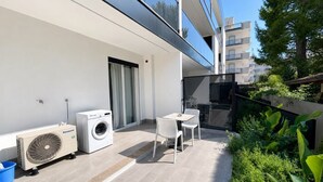 Un balcon équipé d’un lave-linge, d’un ventilateur et d’une table avec des chaises.