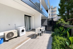 A balcony with a washing machine, a fan, and a table with chairs. - GuestHost - Perla Nera Apartment 7 near the sea (Trani)