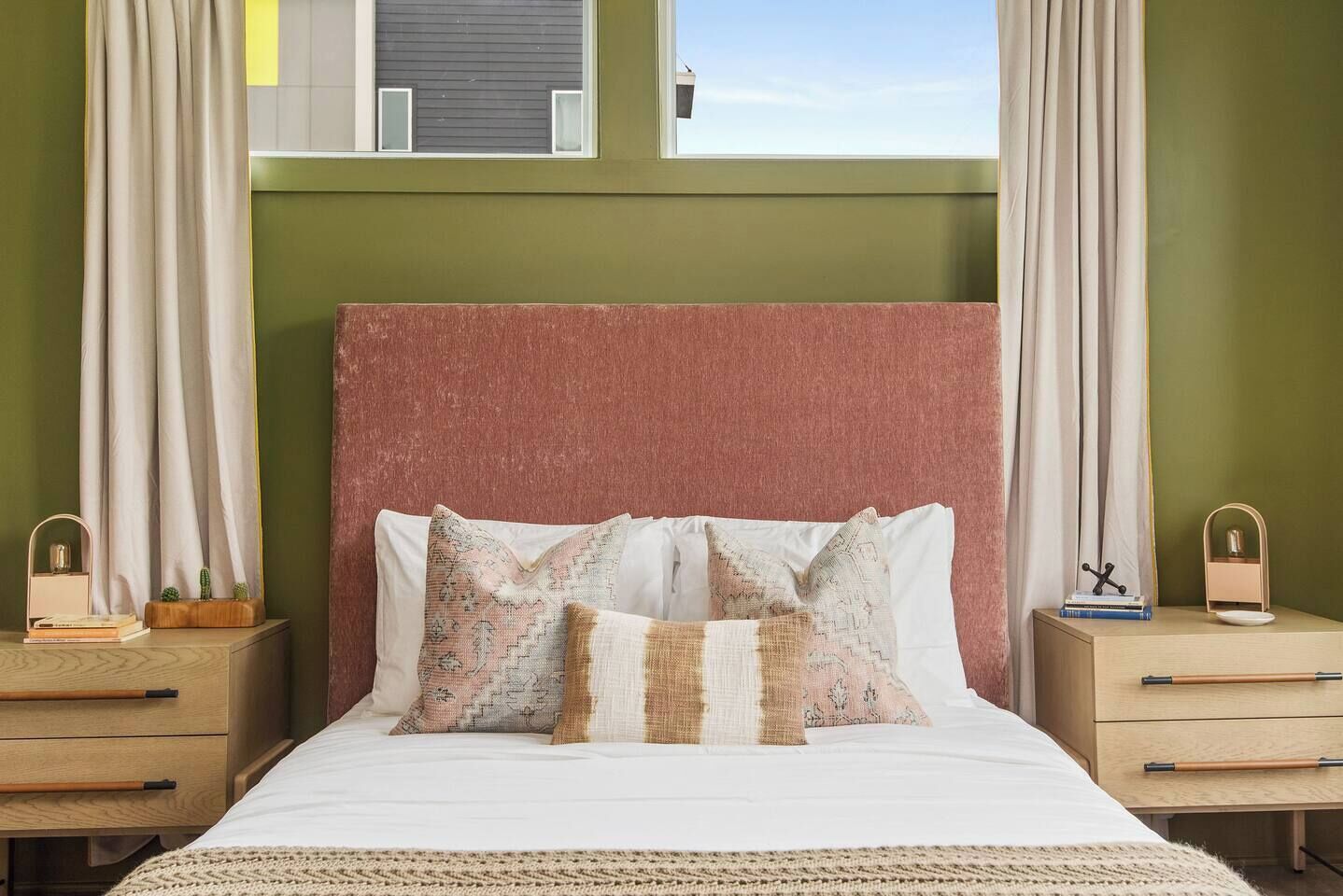 Ein Bett mit weißer Bettwäsche, zwei Nachttische, ein Kopfteil und Vorhänge.
