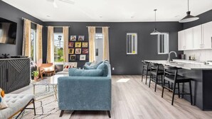 Eine moderne Küche mit Bar, Esstisch und Wohnbereich inklusive Sofa und Fernseher.