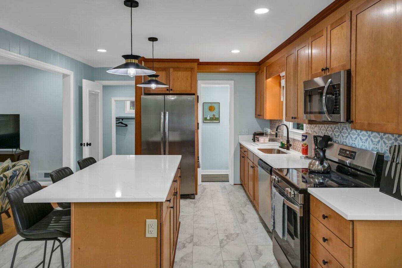 A modern kitchen with wooden cabinets, stainless steel appliances, and a marble island.