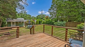 A wooden deck with a railing, a table, and chairs. - The Garden House | Sleeps 11 | Near USC (Cayce)