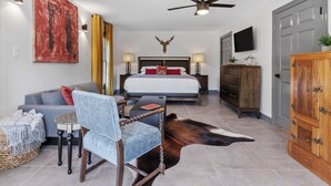 Ein Hotelzimmer mit Bett, Schreibtisch, Stuhl, Fernseher und einem Holzschrank.