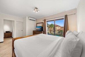 Ein Hotelzimmer mit einem großen Bett, einem Schminktisch, einem Fernseher und Blick ins Freie.