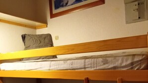 Ein Schlafraum mit Etagenbetten, Holzboden, einem gerahmten Bild an der Wand und einer Steckdose.