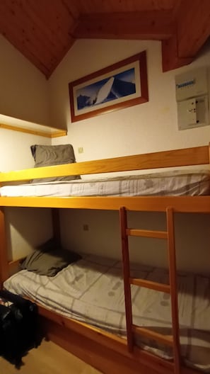 A bunk bed room with a wooden ceiling, a framed picture on the wall, and a power outlet. - Les Contamines-Montjoie, at the foot of Mont Blanc. (Les Contamines-Montjoie)
