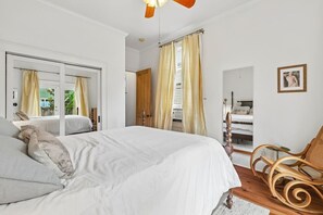 Ein Schlafzimmer mit einem großen Bett, einem Holzstuhl, einem Spiegel und einem Bild an der Wand.