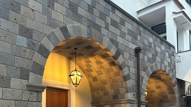Um edifício com paredes de pedra, uma porta de madeira e um candeeiro pendente.