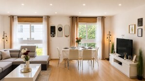 Una sala moderna con sofá, mesa de comedor y televisor.